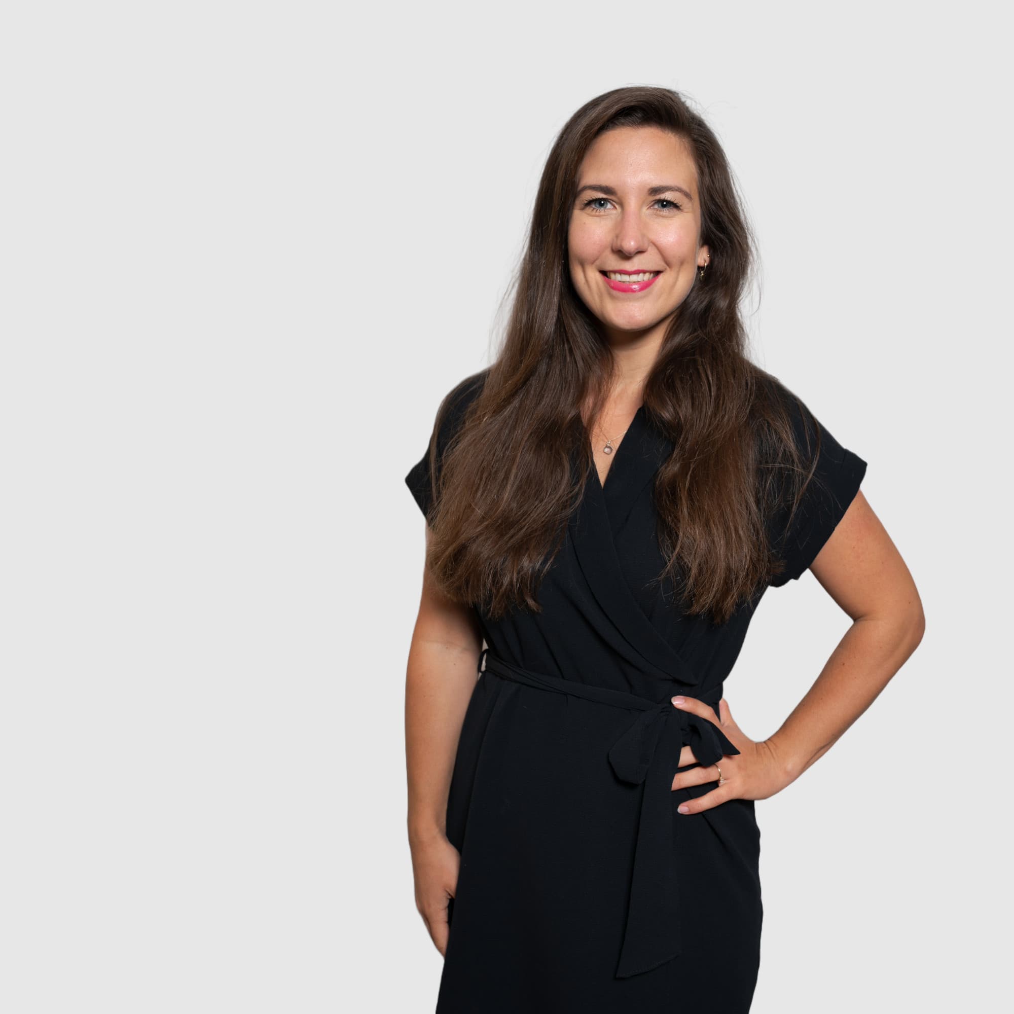 Weibliche Person, die Hände in die Hüften gestemmt, freundlich in die Kamera blickend